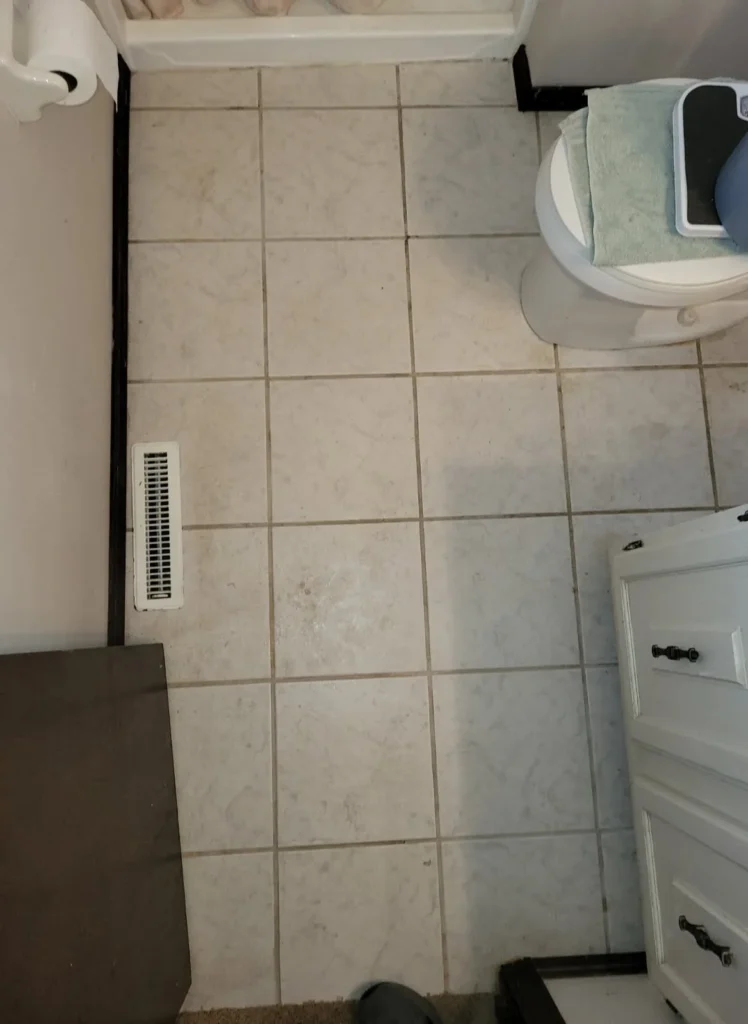 Bathroom tile floor with dirty grout lines before cleaning